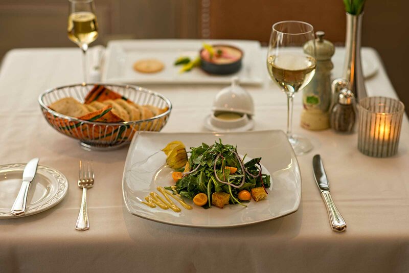 Set table with focus on Mesclun salad with a glass of white wine